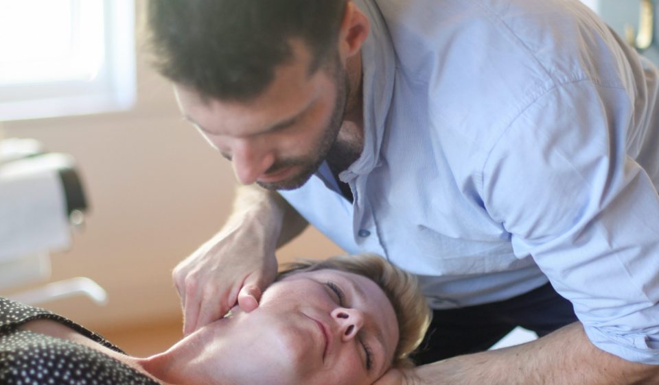 Chiropractor performing a neck adjustment on a patient lying down